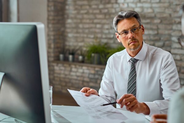 A tax accountant in a white shirt and tie engaged in conversation with a client for tax filing