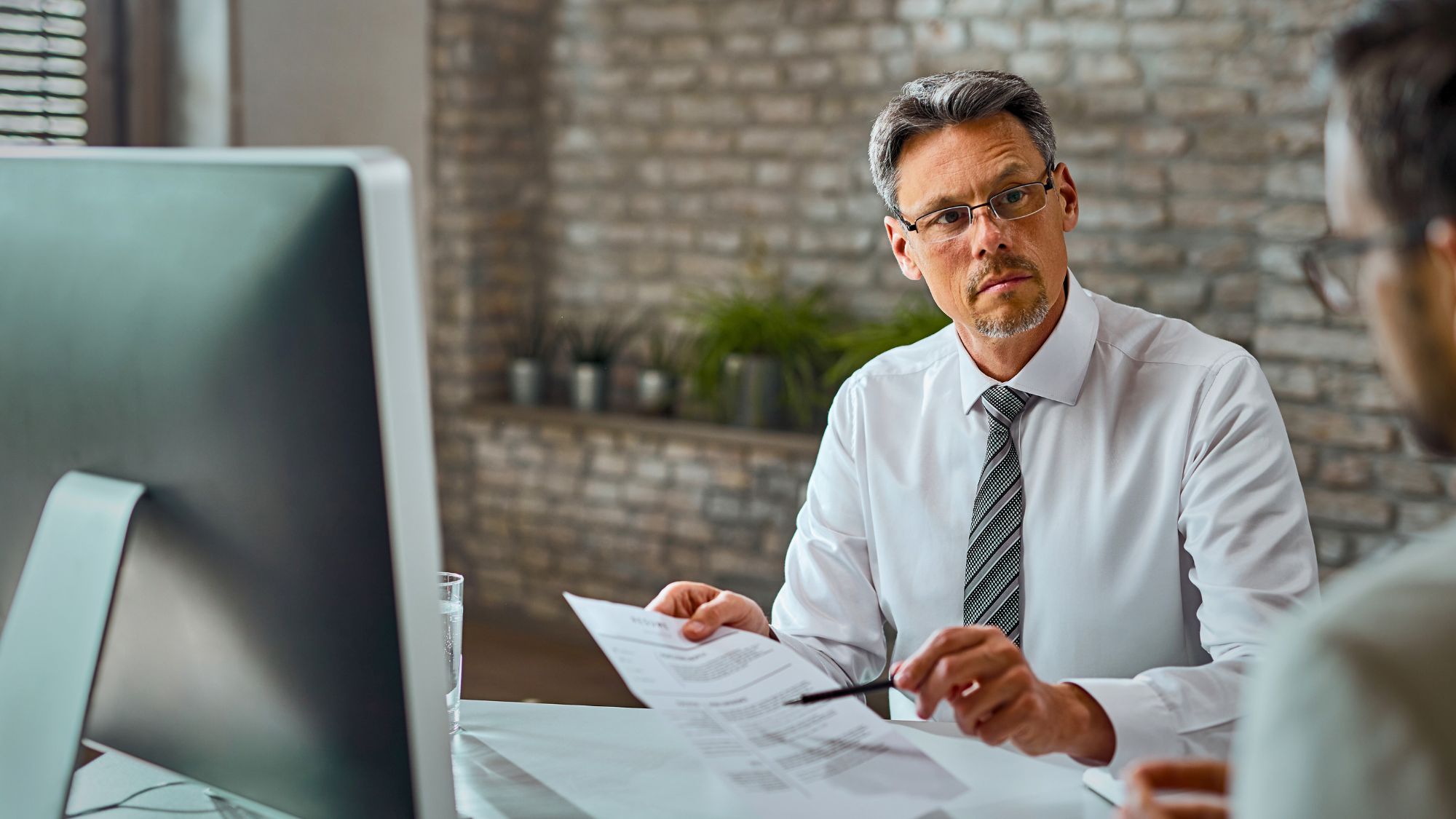 A tax accountant in a white shirt and tie engaged in conversation with a client for tax filing
